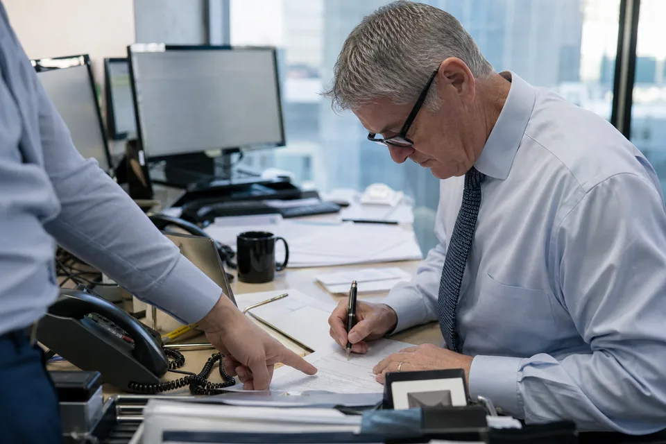 A corporate treasurer marking up a printed bond term sheet and pricing timetable