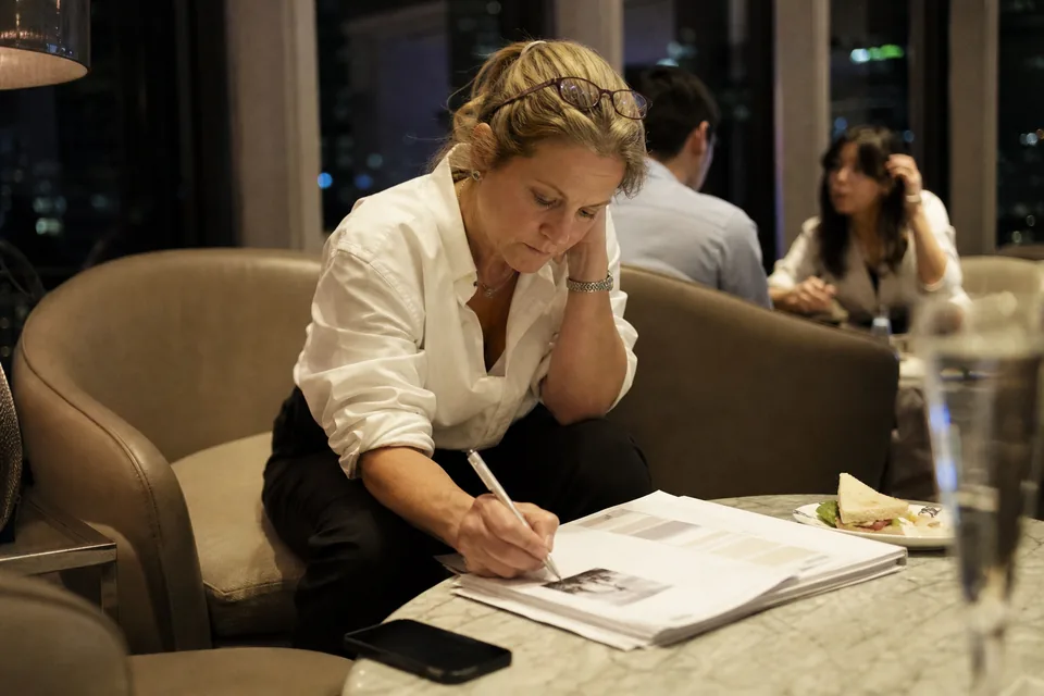 A CFO annotating a printed investor briefing in a hotel lounge in the evening during a roadshow