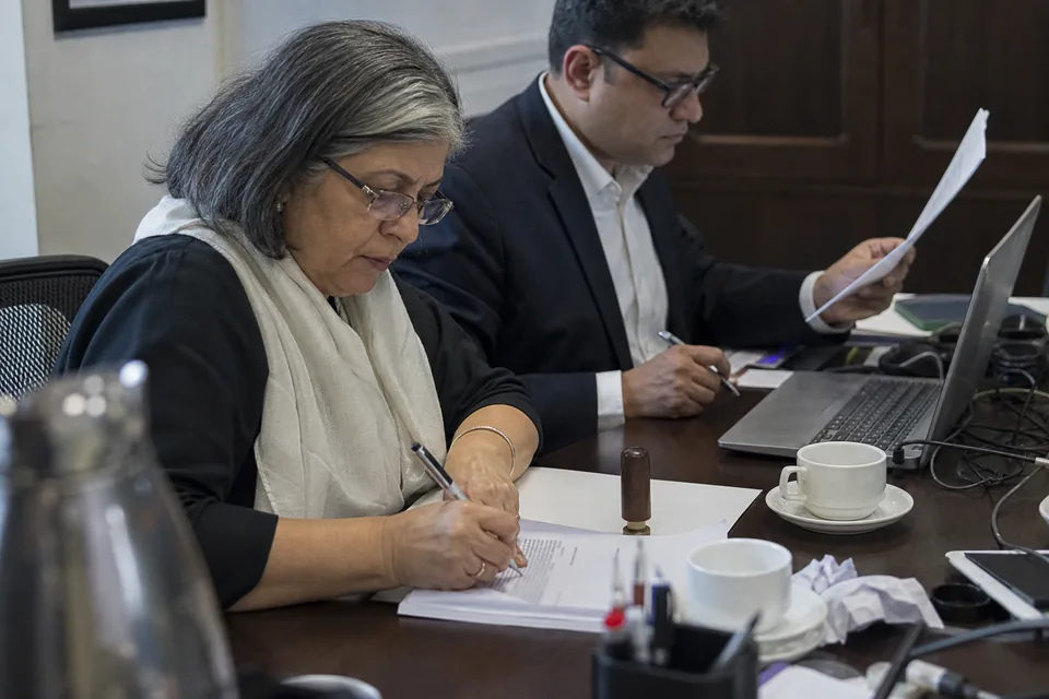 A general counsel and a company secretary reviewing an announcement before approval