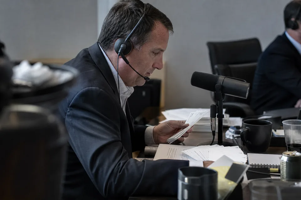 A head of investor relations on an earnings call with a headset, a printed script and question cards