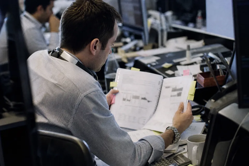 An analyst comparing peer company reports at a desk