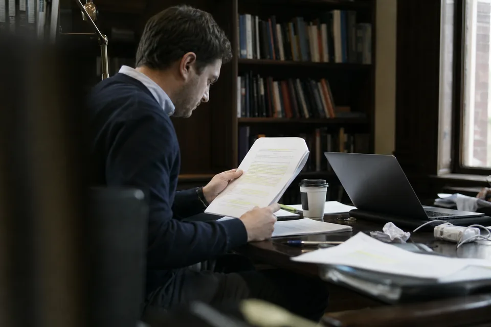 CFO and investor relations lead reading a printed meeting brief together at a desk before a roadshow meeting