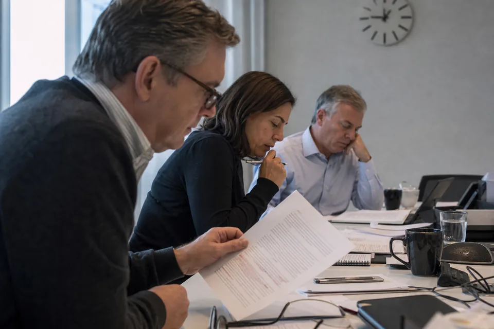 General counsel and finance director reviewing an announcement draft together at a conference table