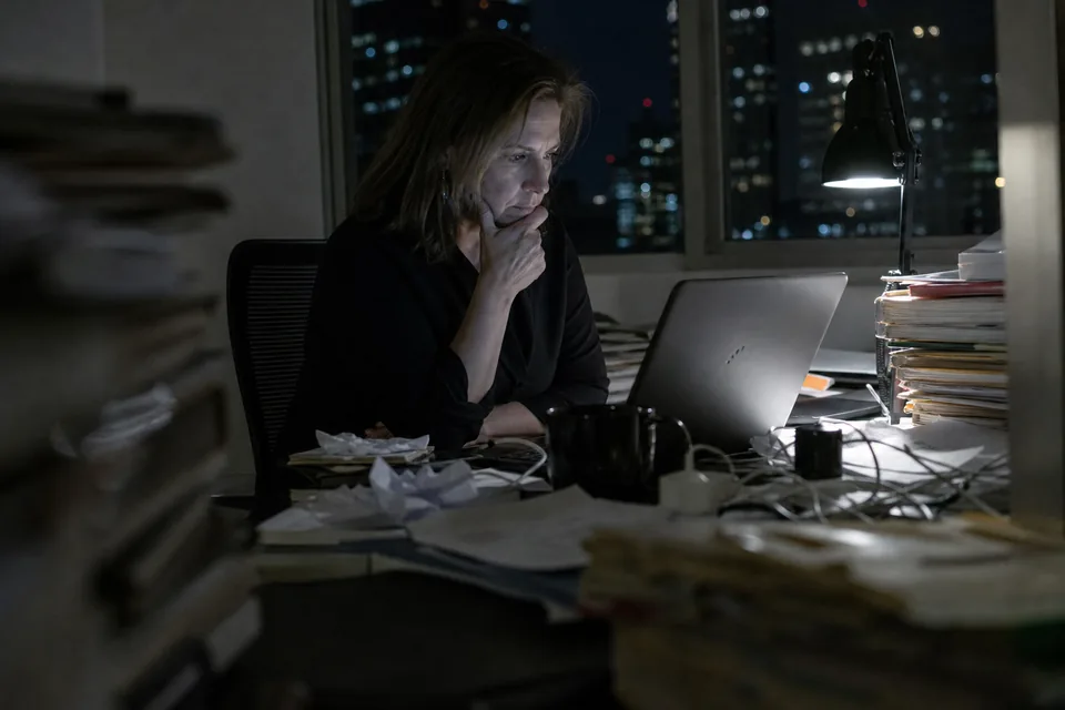 A lawyer reviewing due diligence documents late at night with indexed folders